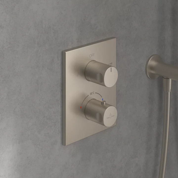 Brushed nickel thermostatic shower valve on a concrete wall