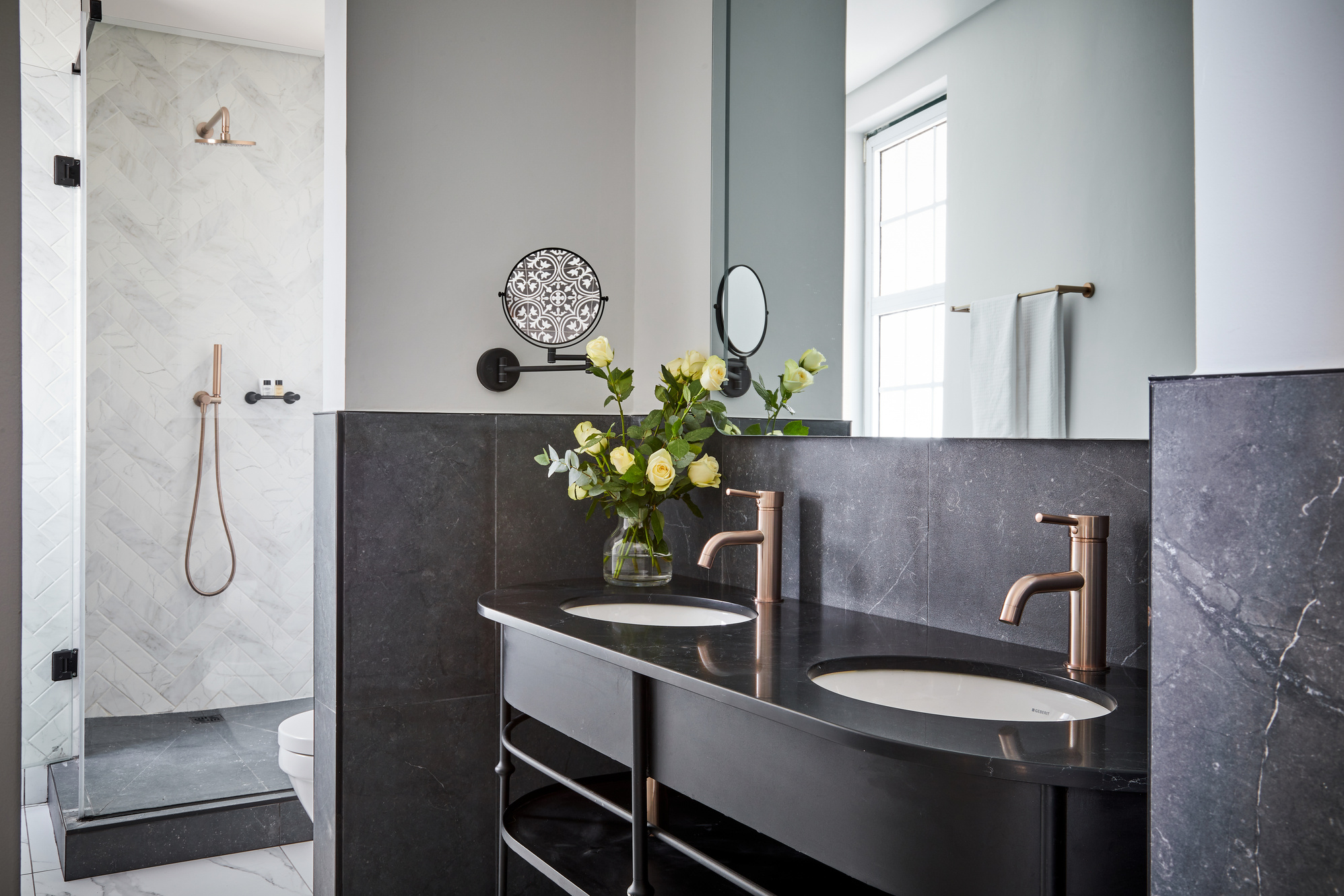 Brushed champagne basin mixers on a dark marble double vanity